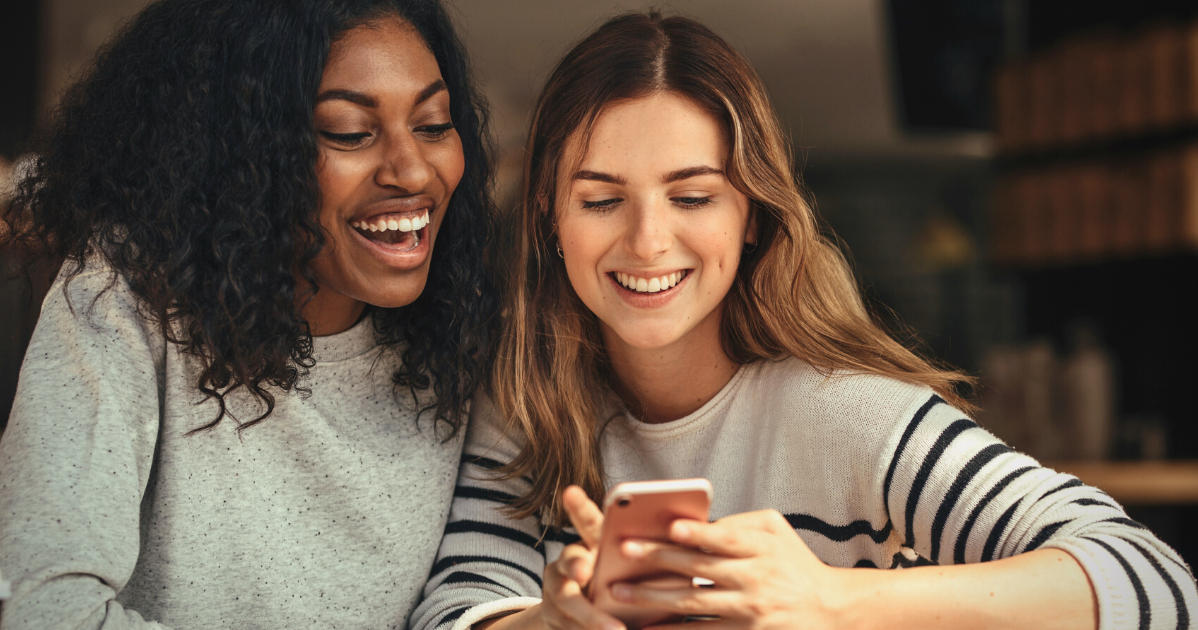 two smiling girls looking at phone