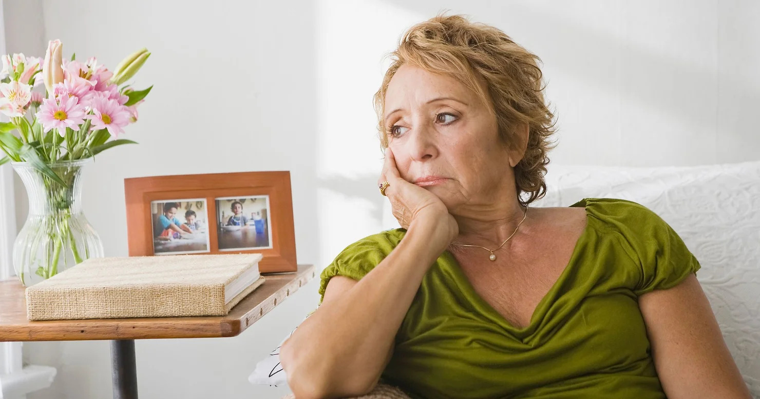 sad older woman sitting on couch