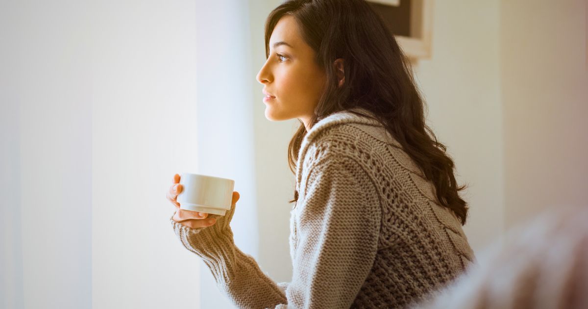 woman holding coffee mug looking out the window